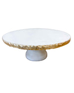 White cake stand with gold rim on a white background